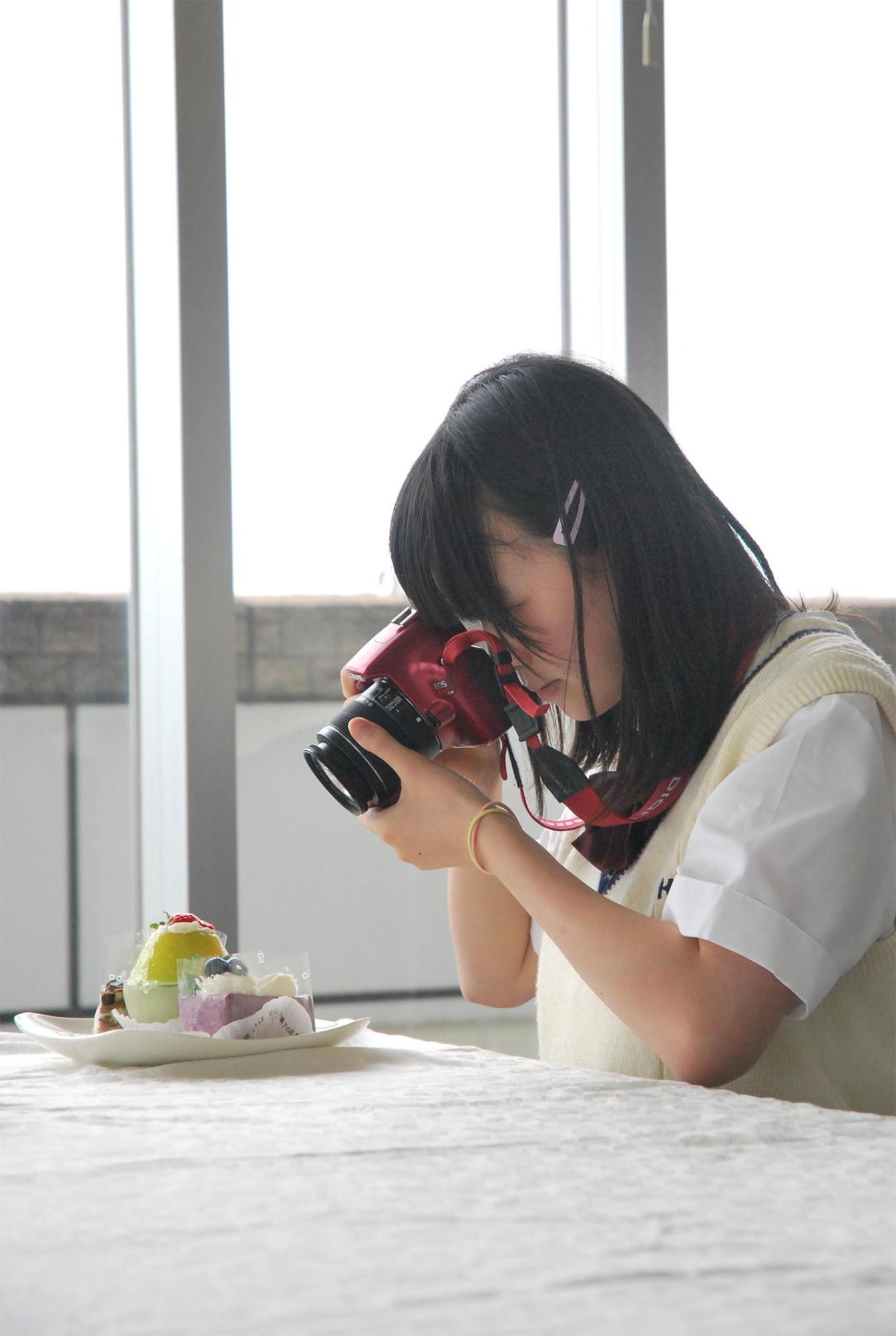 生野高校写真部の女生徒が皿に乗ったケーキを撮影している写真