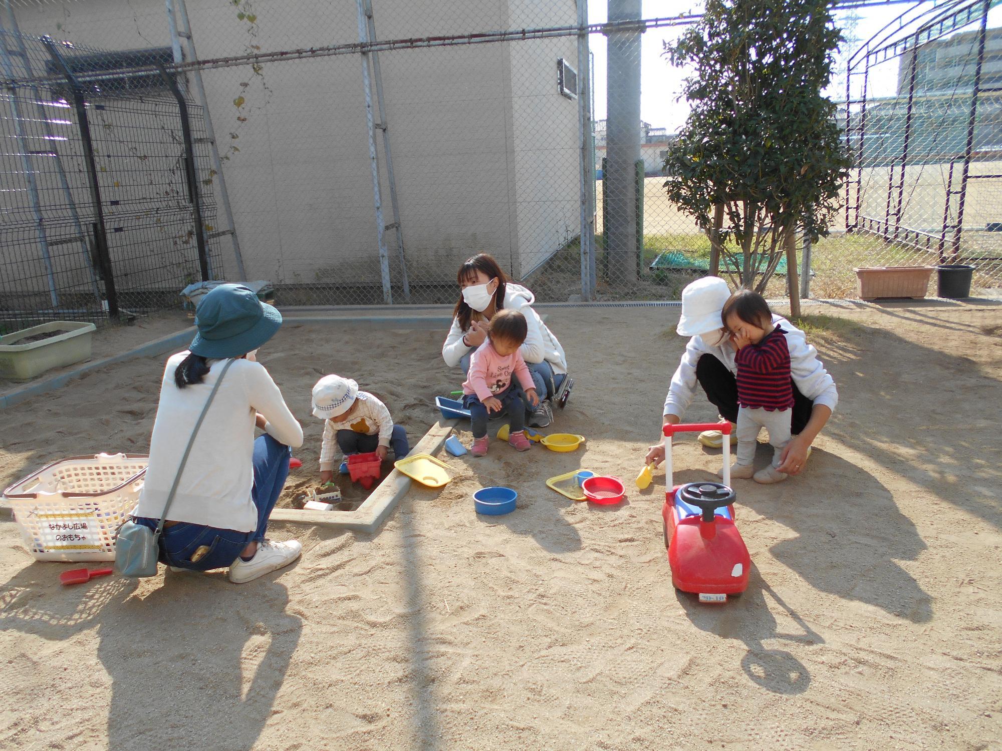 子ども達がお母さんと砂遊びしています