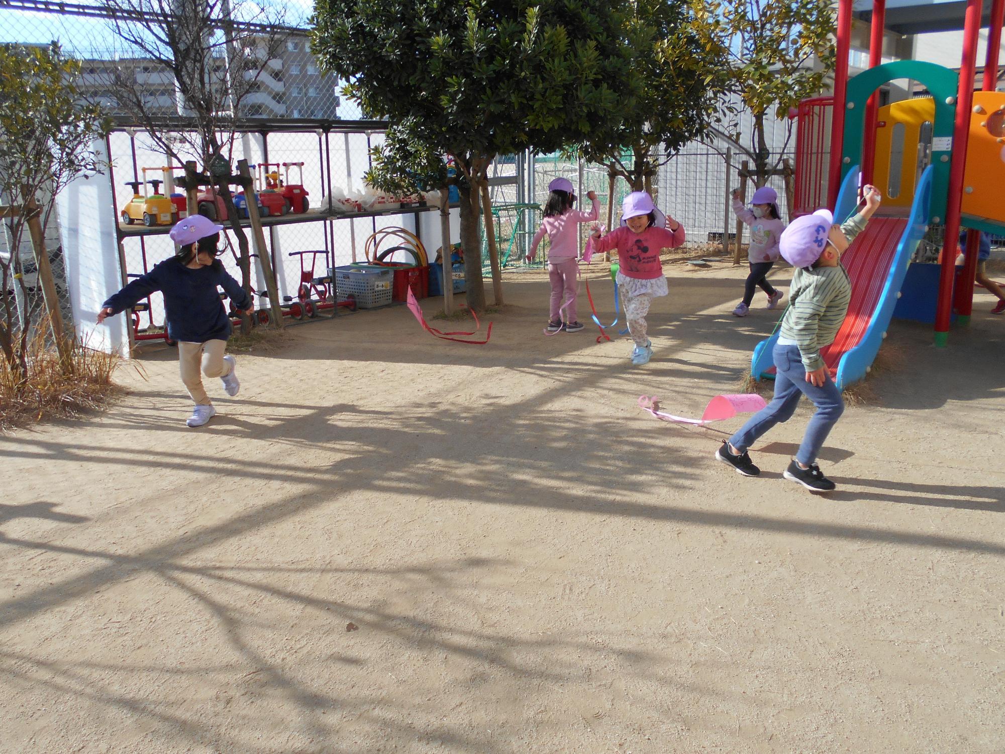子ども達が凧をもって走っています