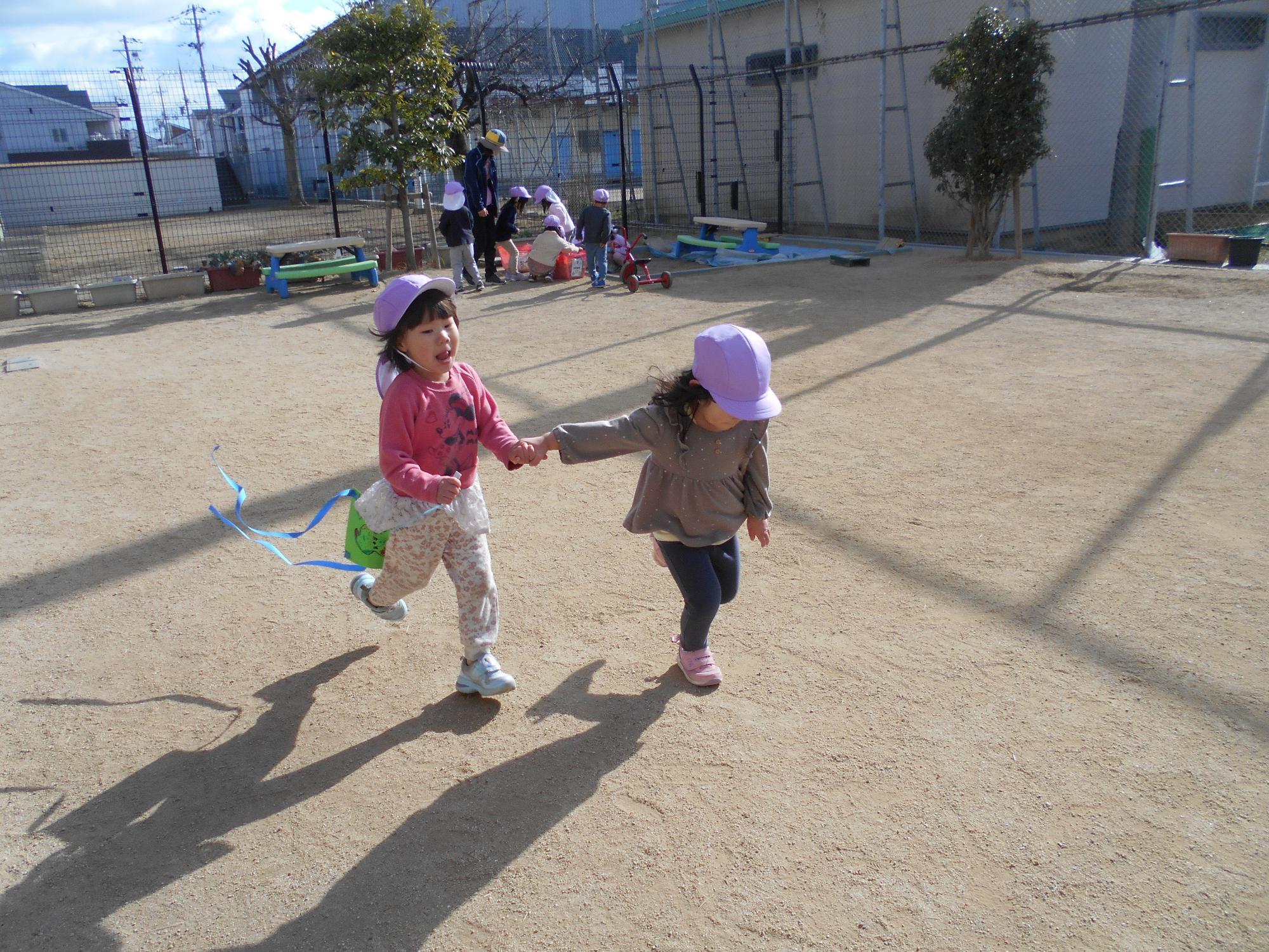 子ども達が2人で手を繋いで凧揚げをしています