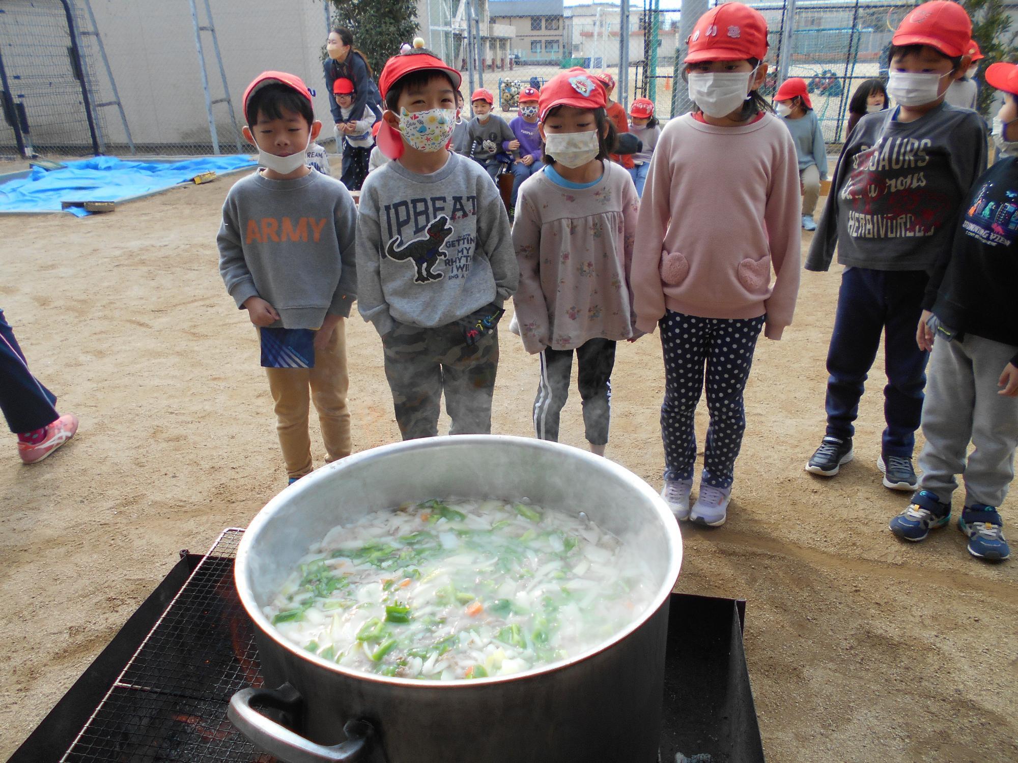 カレーを煮込む鍋を子ども達が見ています